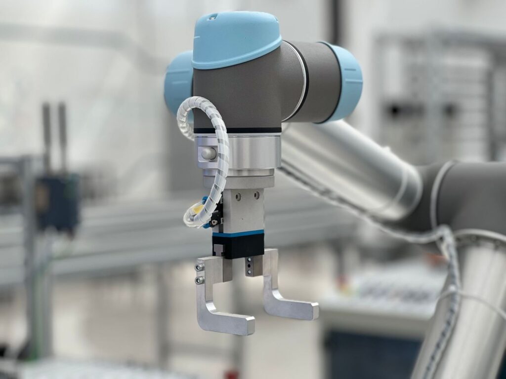 Sinivalkoinen yhteistyörobotin tarttuja tuotantoympäristössä